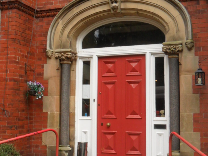 The red front door of Dumbarton House, set in a traditional brick facade.